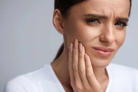 woman holding her face in pain